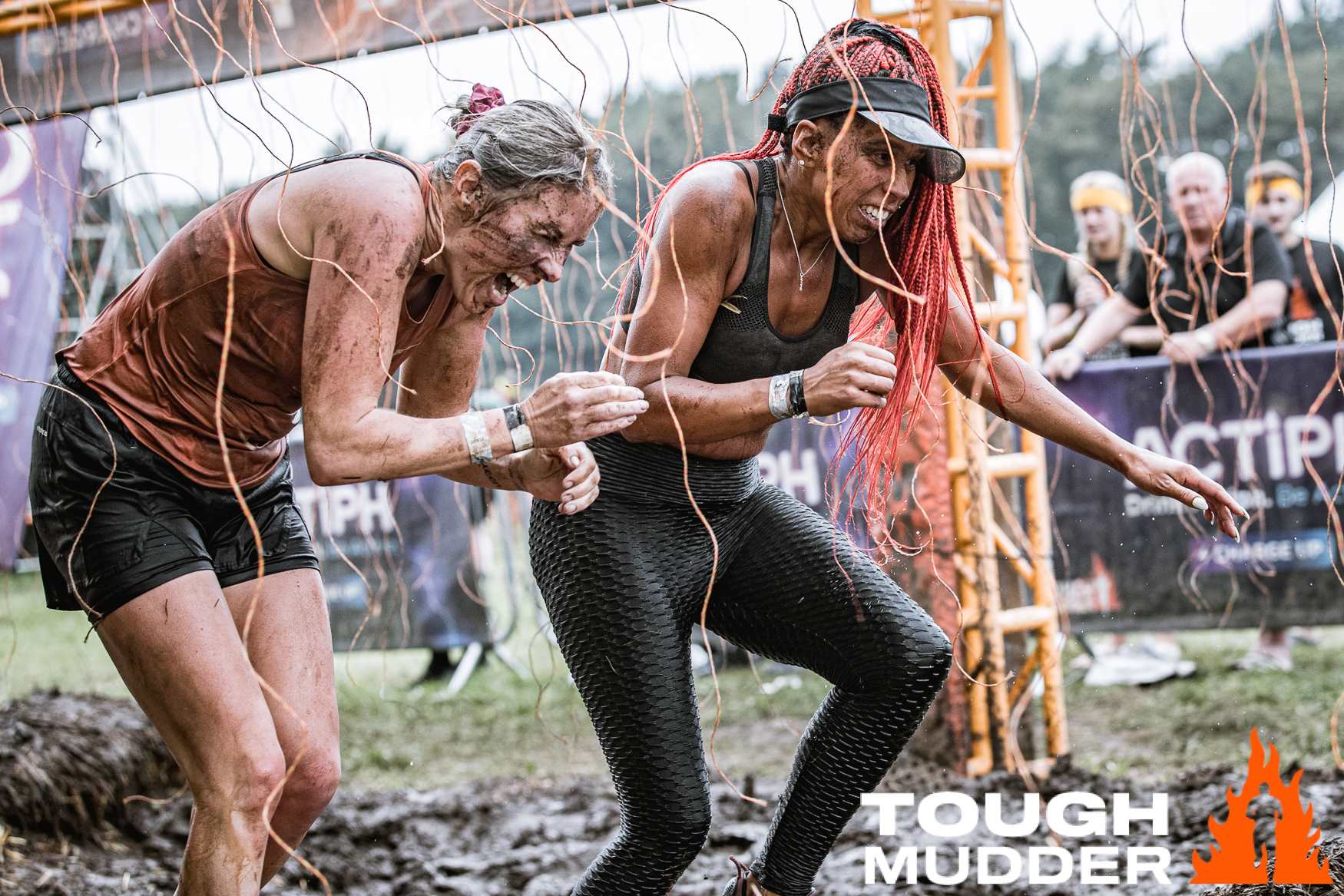 Two Tough Mudder participants running through the course covered in mud