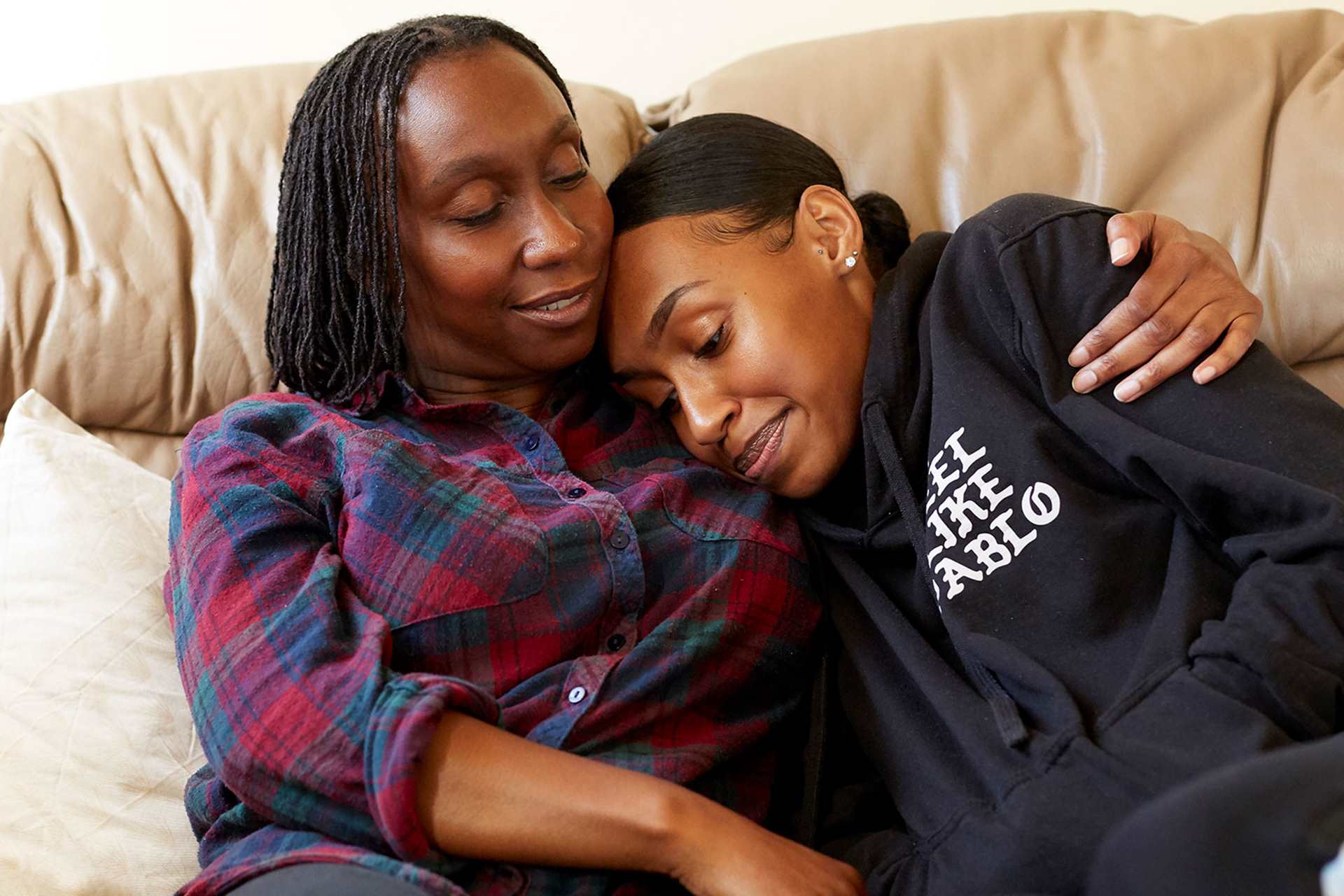 A mother hugging her daughter on the sofa