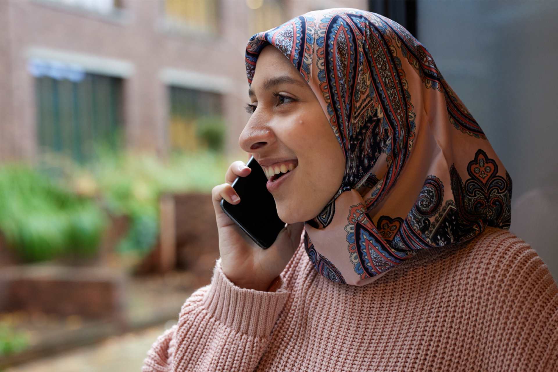 A person wearing a headscarf on the phone.