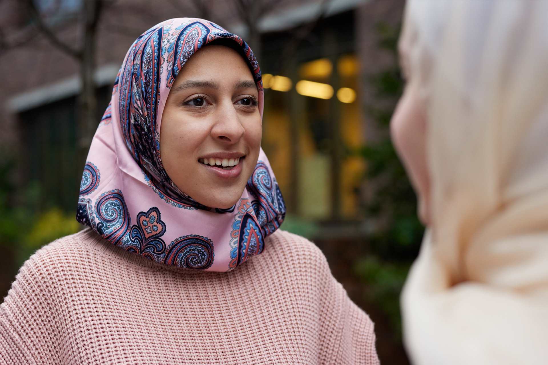 Two young Muslim women in headscarves talking.