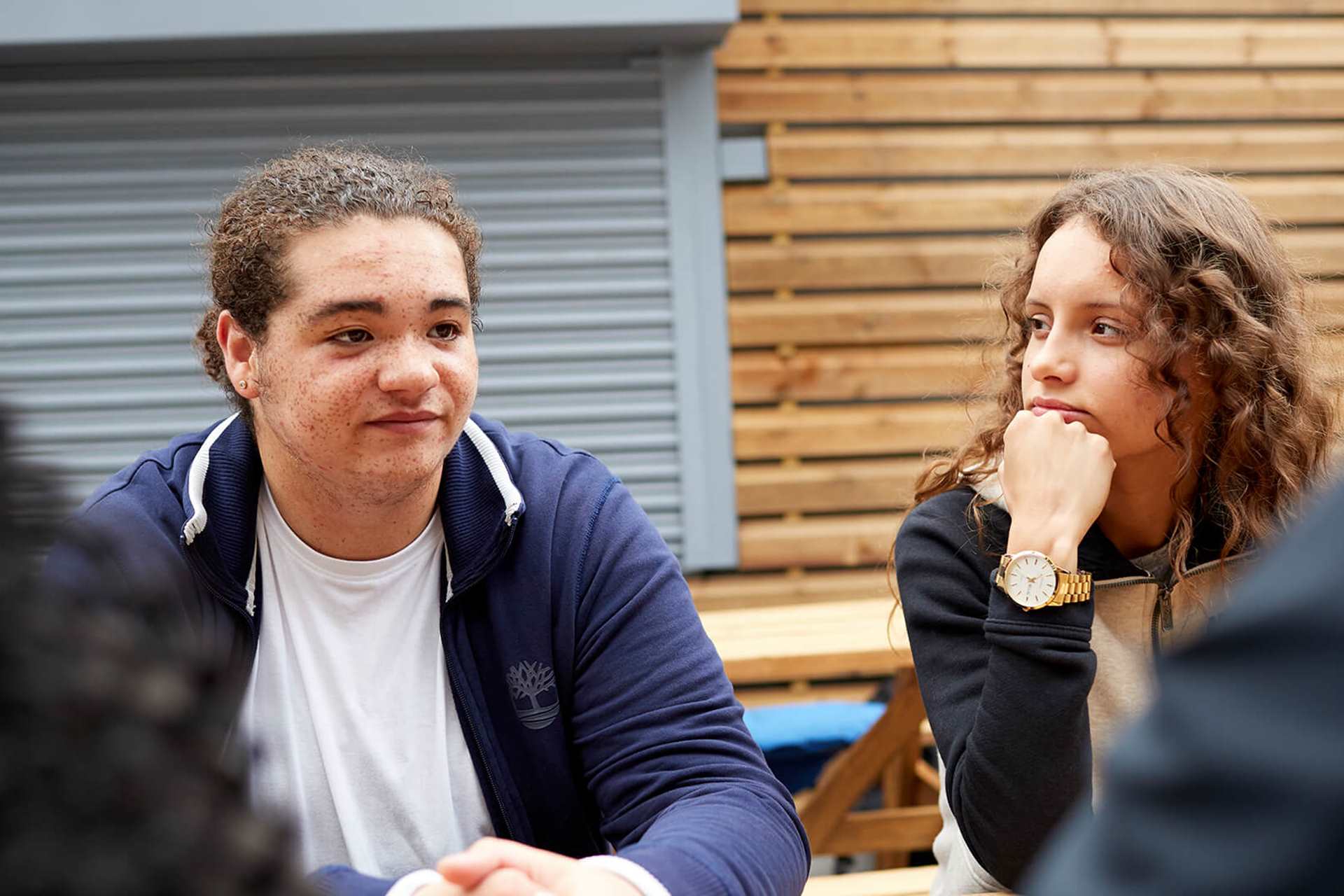 Two young people sitting together at a picnic bench with their friends.