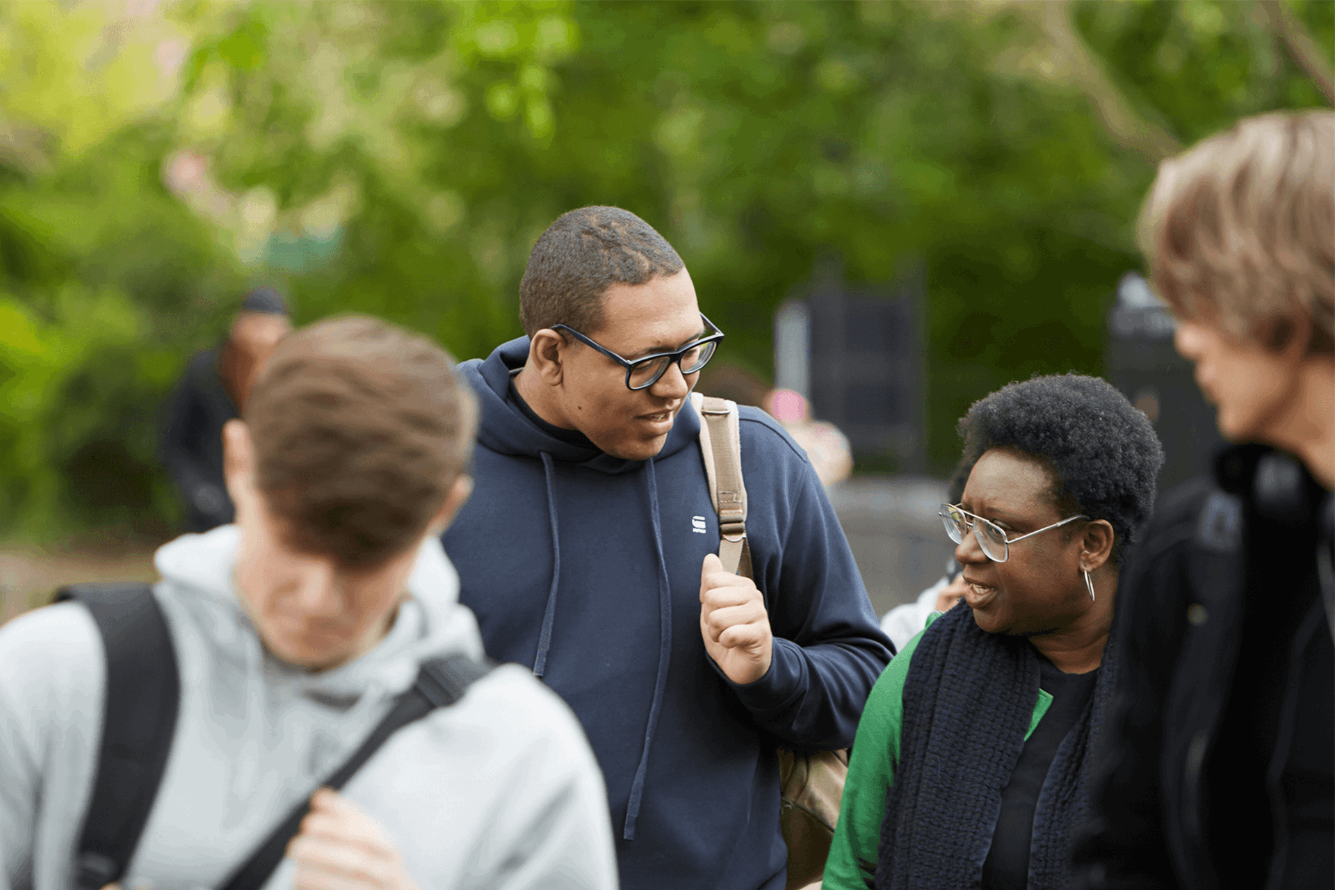 A group of young people talking together as they walk through a college campus.