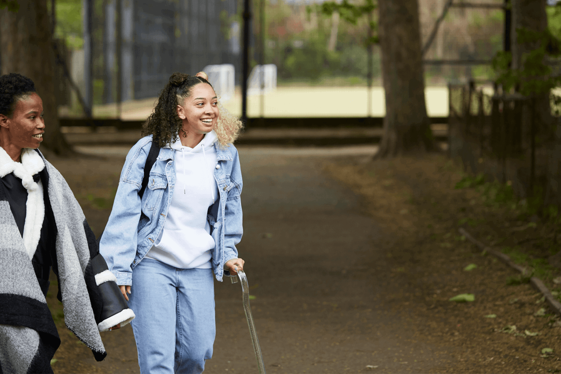 Two young people walking down a park path together.