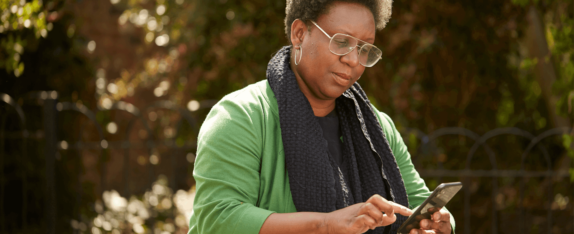 A lady typing on her phone while sitting at a picnic table
