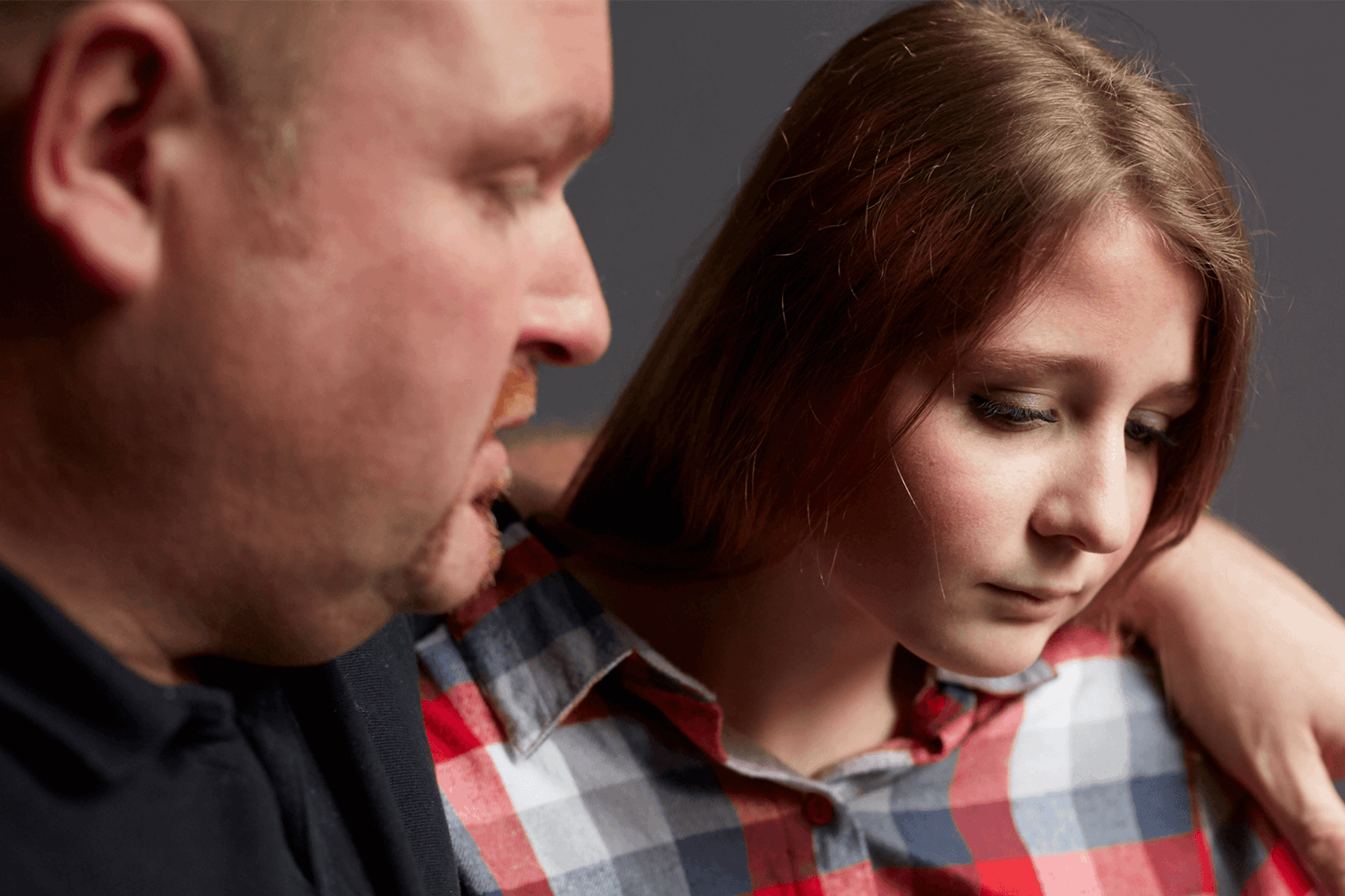 A father comforting his sad daughter with his arm around her