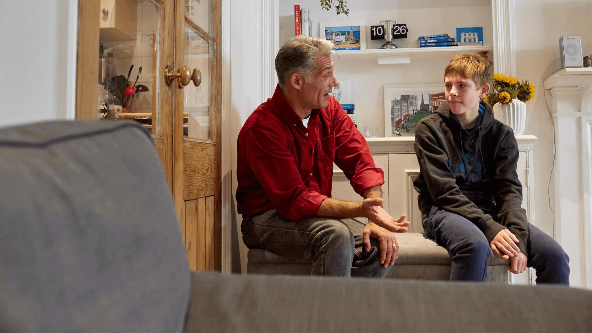 A father and son talking in a lounge seated 