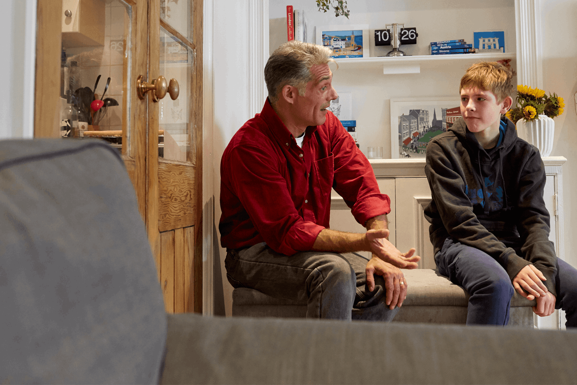 A father and son talking in a lounge seated 