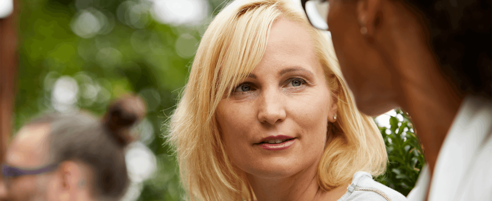 Two women outside in deep conversation with a tree behind them 