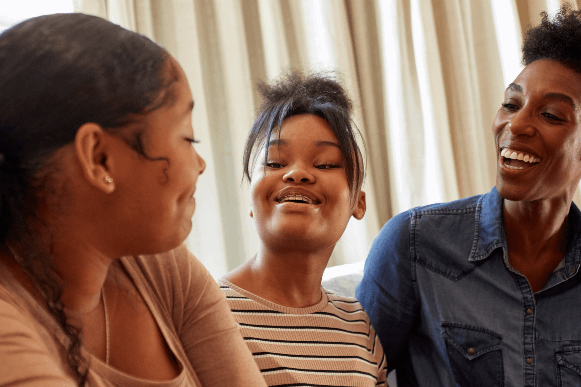 A mother and her two daughters smiling and laughing together.