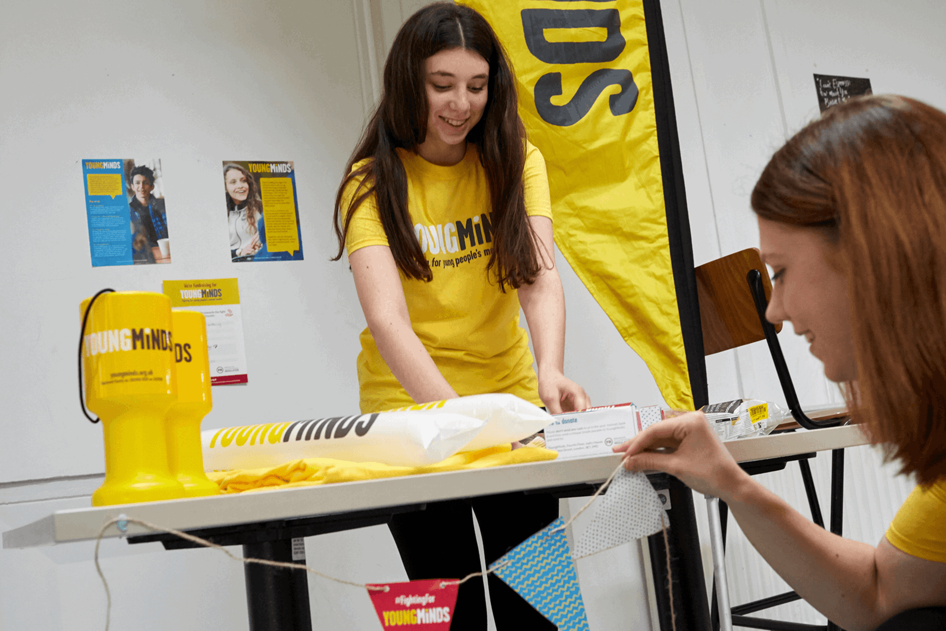 two girl volunteers are tidying up YoungMinds fundraising materials