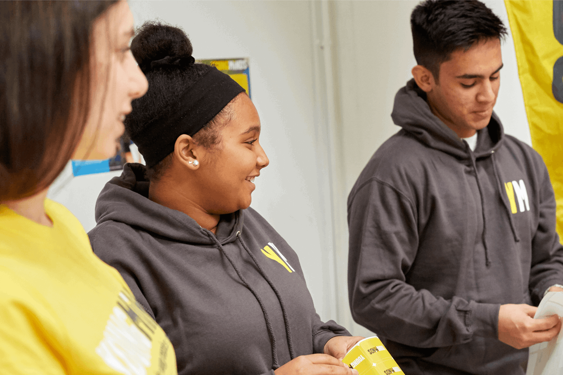 three young people fundraising volunteers wearing YoungMinds hoodie smiling