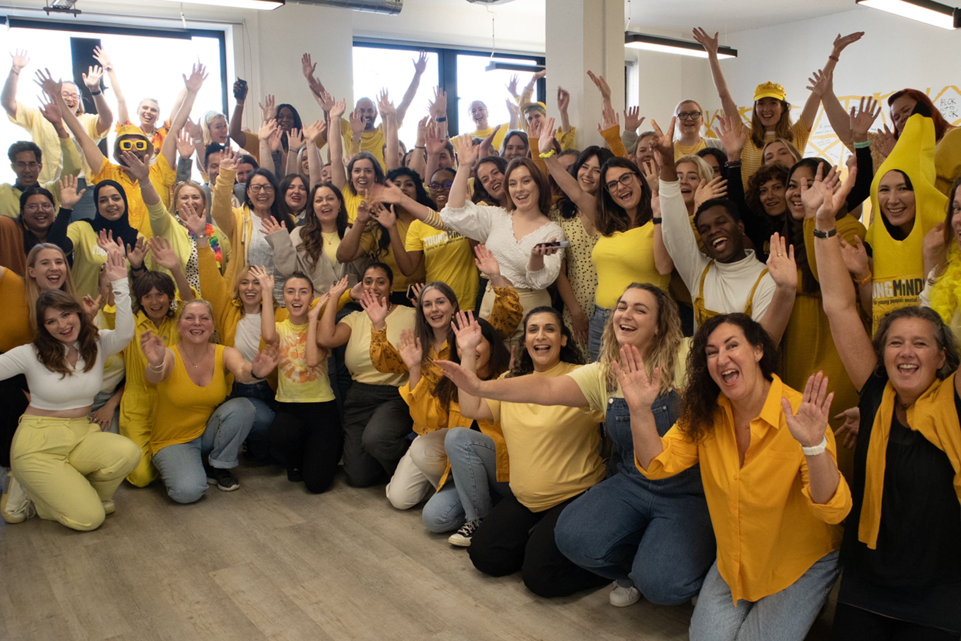 YoungMinds staff all wearing yellow for #HelloYellow 2023, posing with their hands in the air.