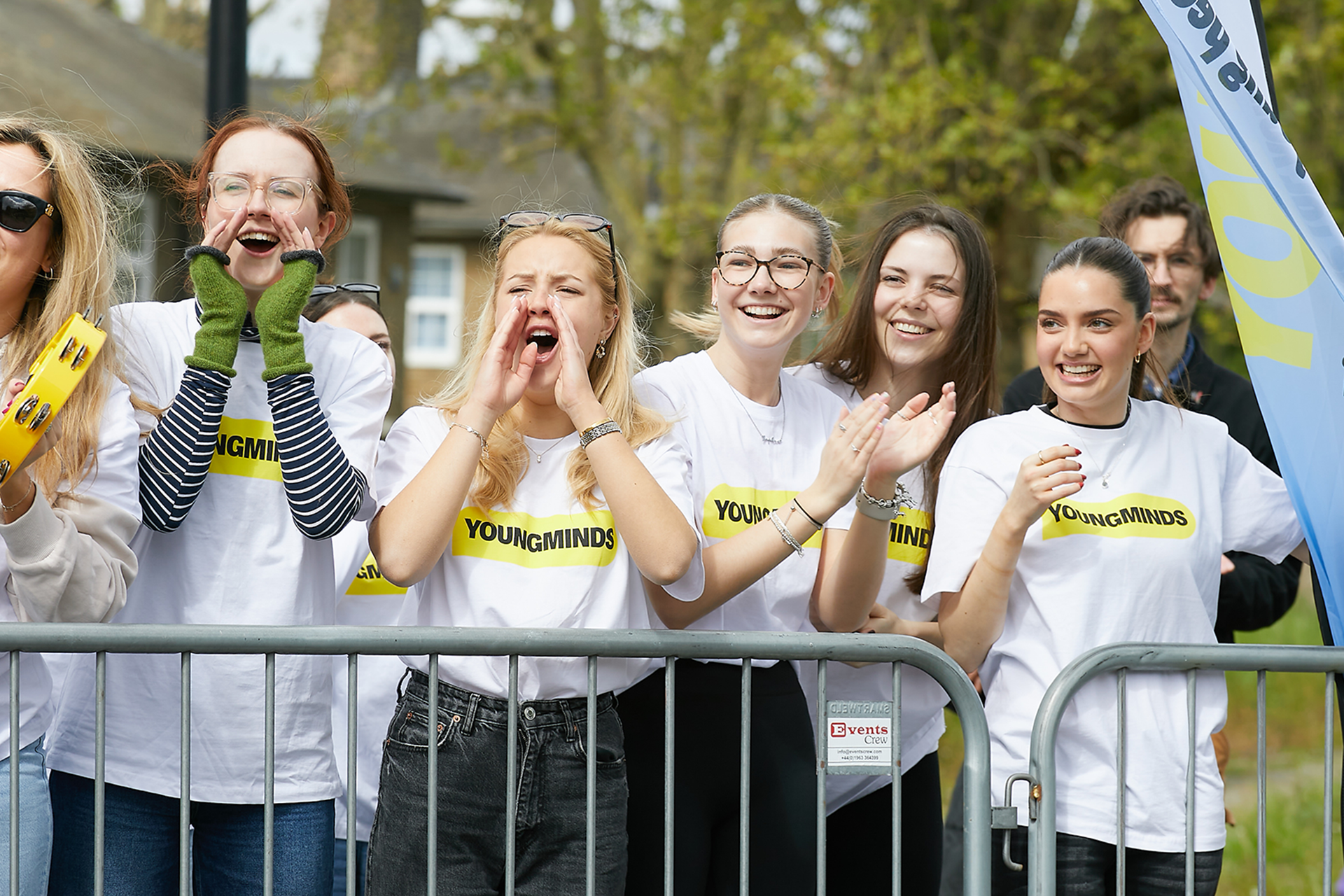YoungMinds staff cheering marathon runners on from the side line in YoungMinds t-shirts and with YoungMinds banners.