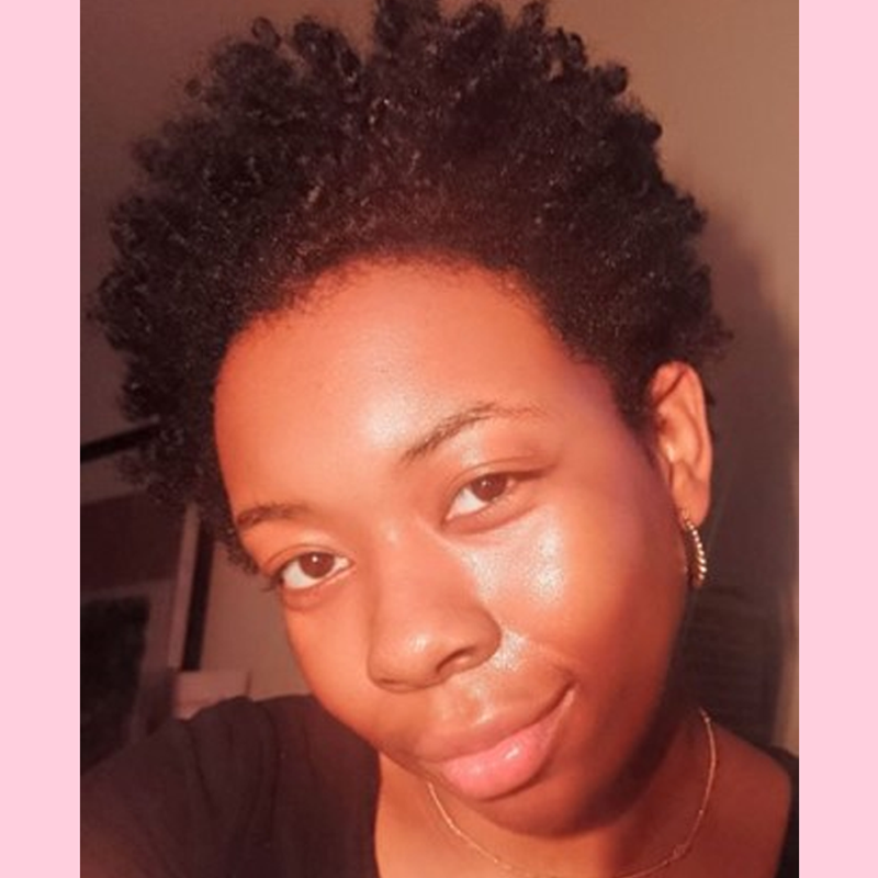 Neka is looking at the camera wearing a necklace and a black tshirt.