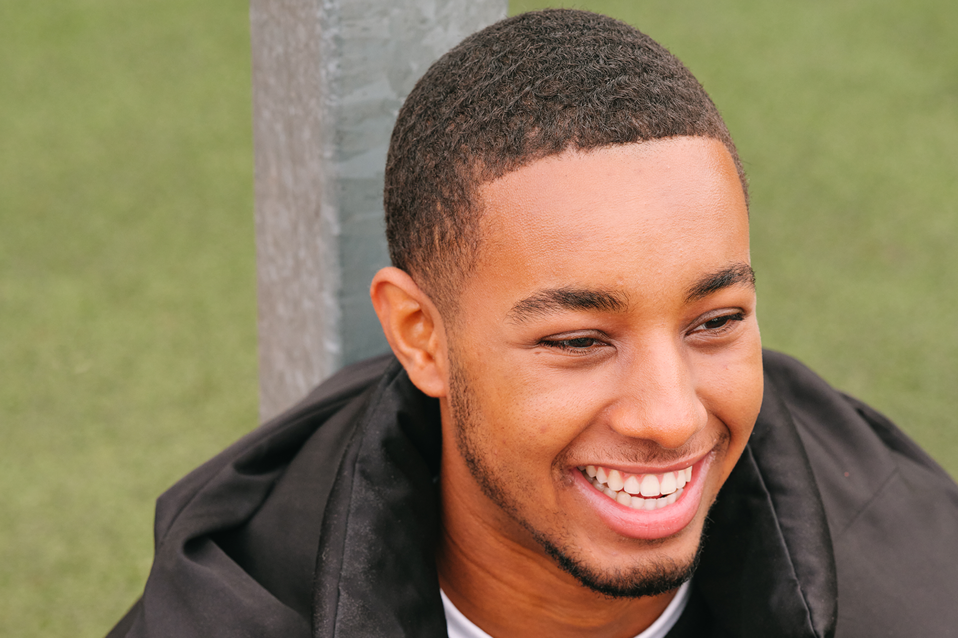 A young Black man smiling in the park.